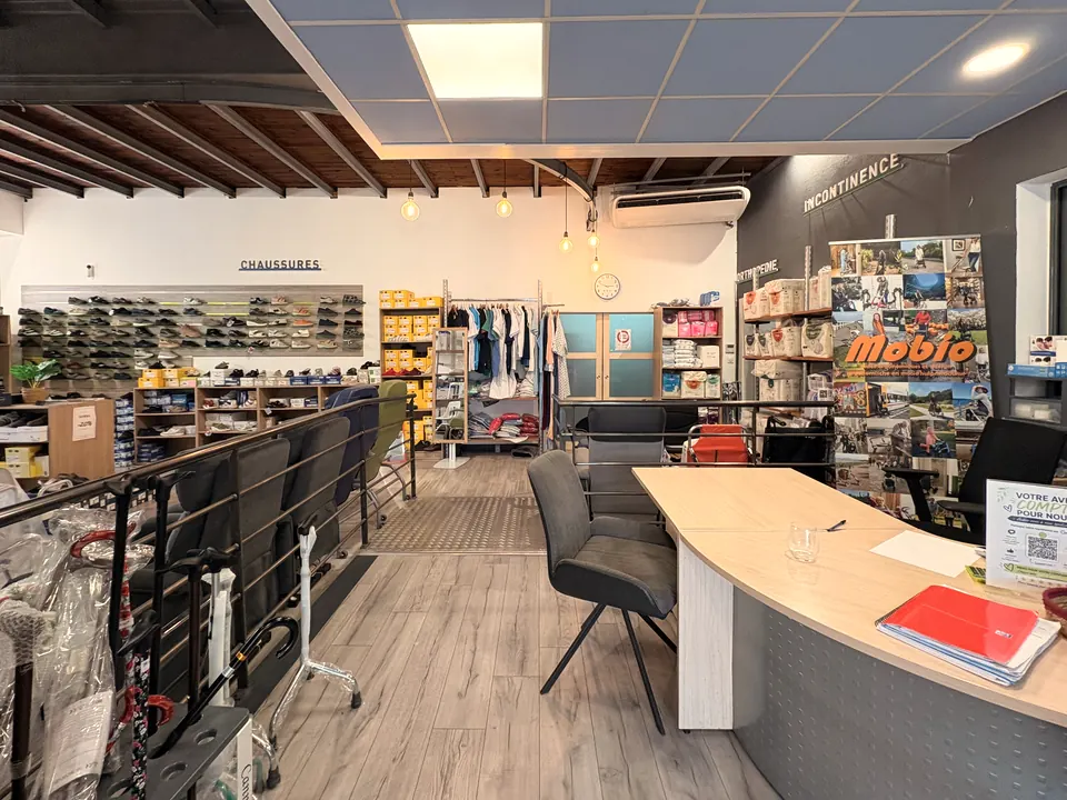 L’espace conseil du magasin : un bureau en bois clair, deux chaises, le mur de chaussures thérapeutiques en arrière-plan